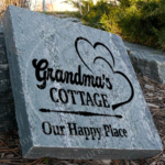 Engraved granite cottage garden accent stone feature with "Grandma's Cottage, Our Happy Place" and two hearts place outside.