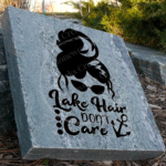 Engraved granite cottage lake accent stone feature with "Lake Hair Don't Care" and woman with messy hair, sunglasses, also anchor near walkway .