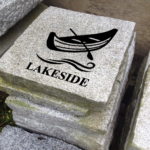 Engraved granite cottage stone with canoe and waves design that says lakeside.