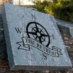 Engraved granite cottage stone with compass that shows north, south, east and west design that says the retreat.