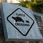 Engraved granite stone with turtles crossing design.