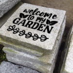 Engraved granite garden accent stone feature with "Welcome to my Garden" and leaves design placed outside.
